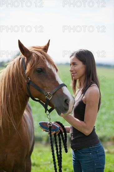 Young woman taking care of horse. Photo : Jan Scherders