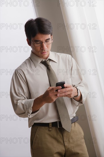 Young businessman using cell phone. Photo : Rob Lewine