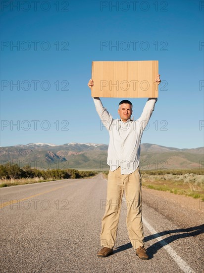 Mid-adult man hitch-hiking in barren scenery. Photo: Erik Isakson