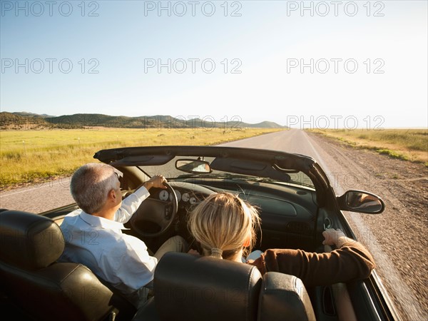 USA, Utah, Kanosh, Mad-adult couple driving through desert plains in convertible car.