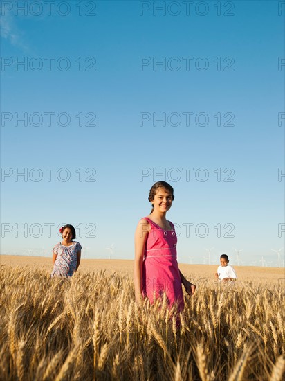 Girls (10-11, 12-13) and boy (8-9) standing in wheat field. Photo: Erik Isakson