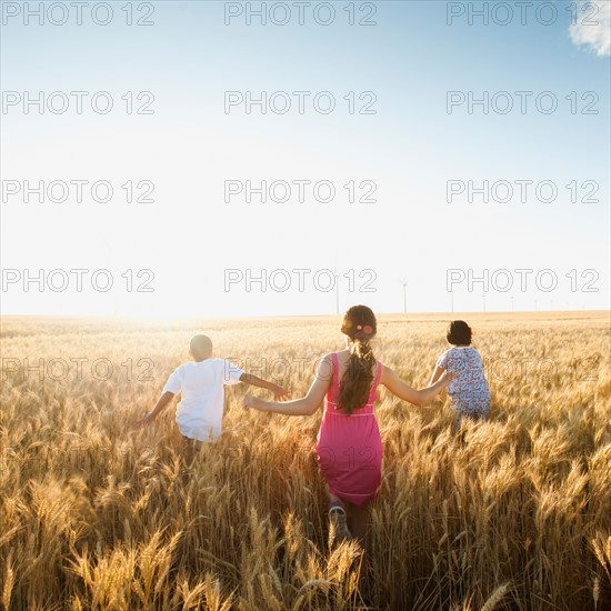 Girls (10-11, 12-13) and boy (8-9) walking though wheat field. Photo: Erik Isakson