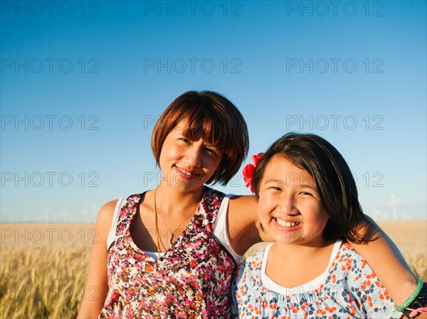 Mother and daughter (10-11) standing in wheat field .