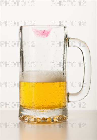 Lipstick on beer glass, studio shot.