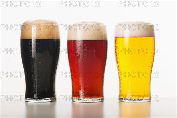 Three beers in glasses, studio shot.