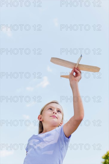 Girl (10-11) playing with toy plane.