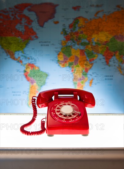 Studio shot of red phone in front of world map.