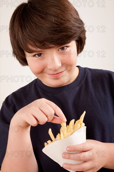 Studio portrait of boy (10-11) holding french fries. Photo: Rob Lewine