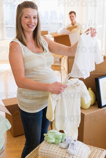 Young couple unpacking baby clothing.