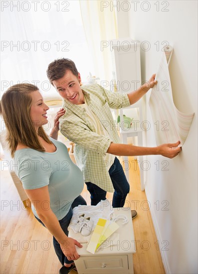 Young couple choosing wallpaper for nursery.