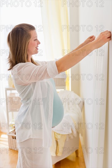 Young woman choosing wallpaper for nursery.