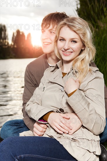 Portrait of young couple embracing by lake at sunset. Photo : Take A Pix Media