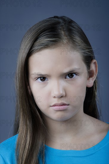 Portrait of girl (8-9) looking angry, studio shot. Photo : Rob Lewine