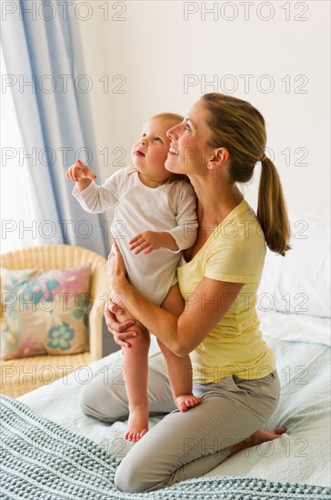 Mother with daughter (2-3) on bed.