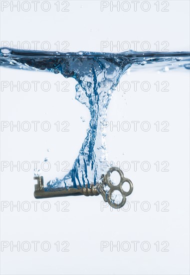 Silver key splashing into water, studio shot. Photo : Daniel Grill