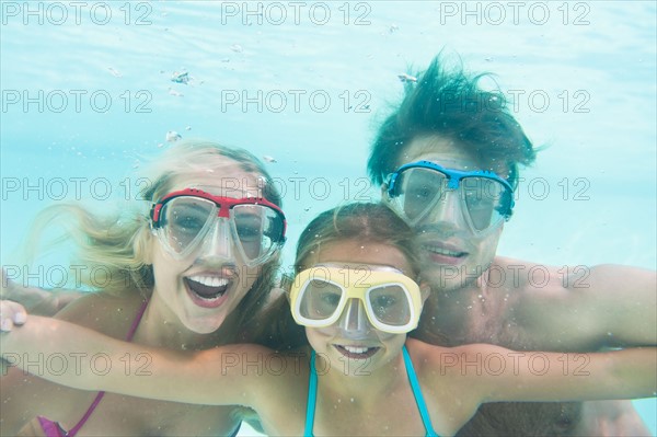 Parents with daughter (10-11) swimming underwater. Photo : Daniel Grill