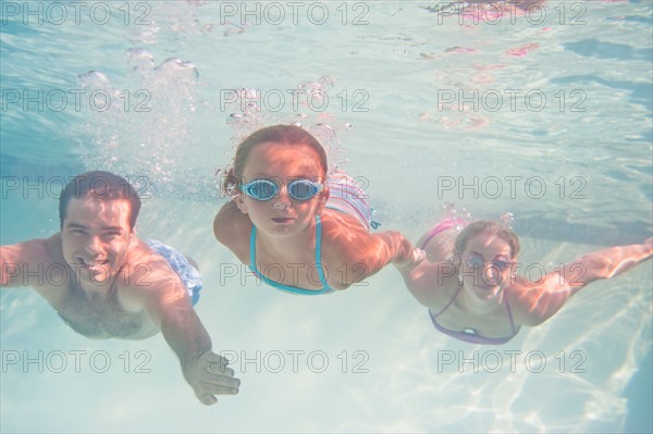 Parents with daughter (10-11) swimming underwater. Photo : Daniel Grill