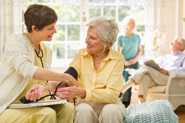 Nurse taking pulse of senior woman in nursing home.