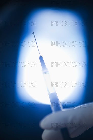 Studio shot of hand holding syringe.