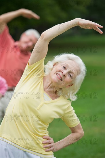 Seniors stretching in park.