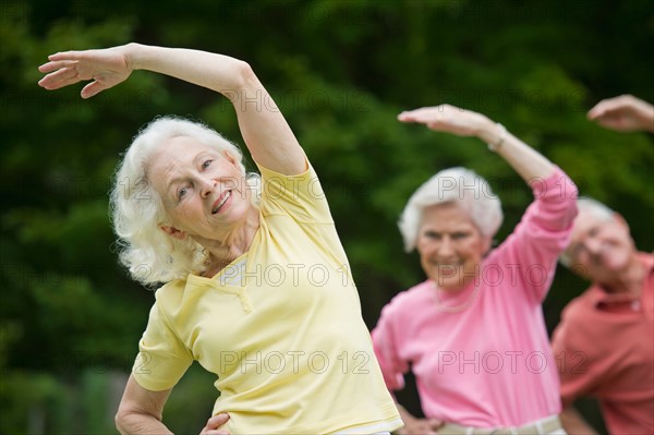 Seniors stretching in park.