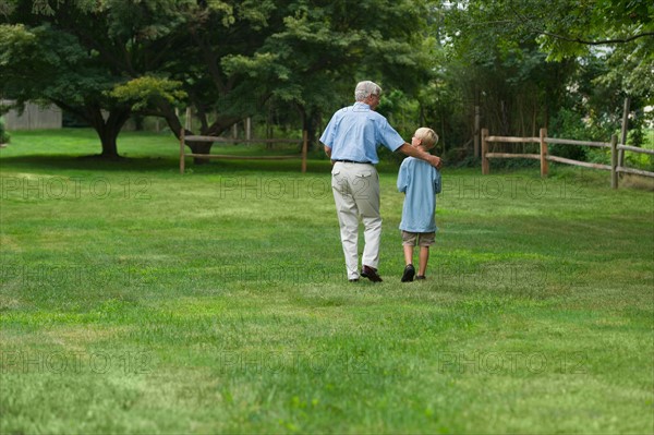 Grandfather and grandson (10-11) walking in park.