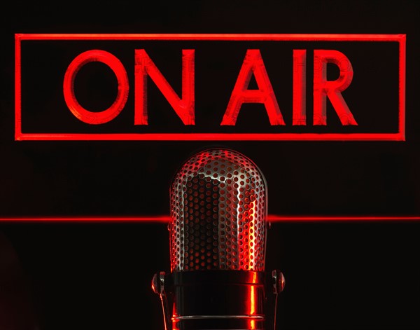 Vintage microphone and red on air neon, studio shot.