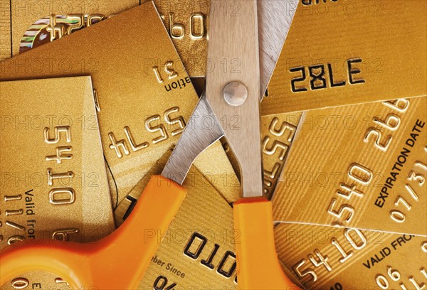 Scissors on pile of credit cards, studio shot.