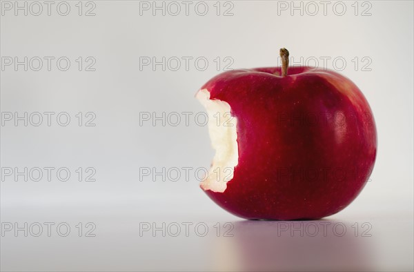 Red apple with missing bite, studio shot.
