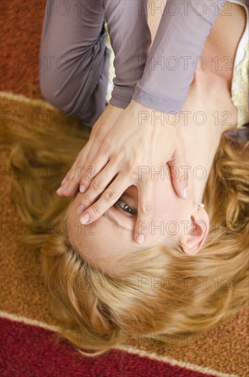 Woman lying on floor covering eyes.