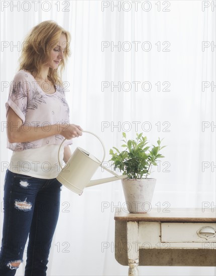 Woman watering plant at home.