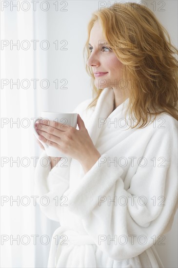 Woman in bathrobe drinking coffee.