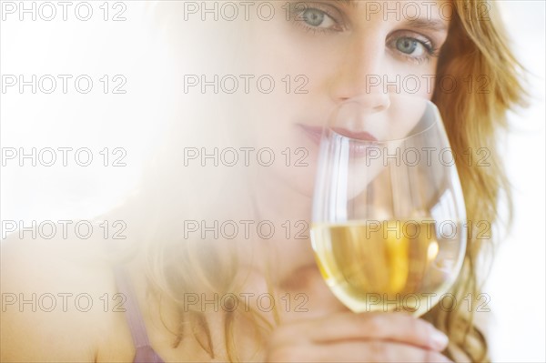 Portrait of young woman tasting wine, studio shot.