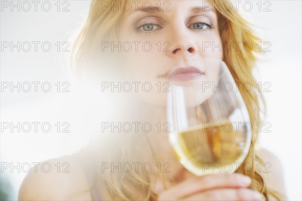 Portrait of young woman smelling wine, studio shot.