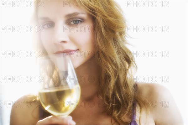 Portrait of young woman smelling wine, studio shot.