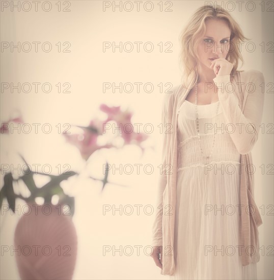 Studio portrait of young woman standing behind vase.