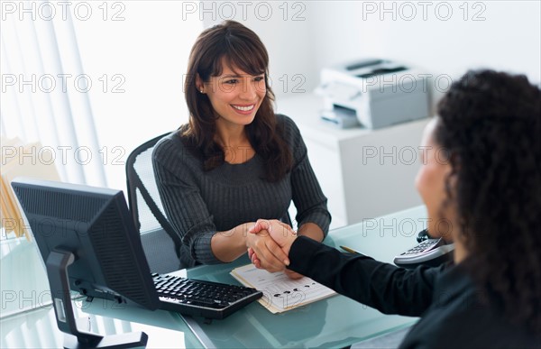 Business women shaking hands in office.