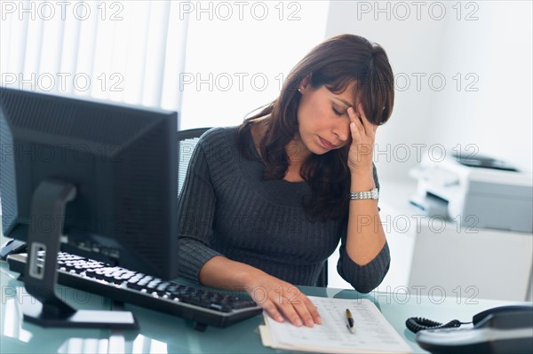 Business woman using computer, looking tired.