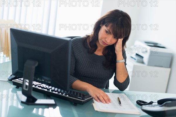 Business woman using computer, looking tired.