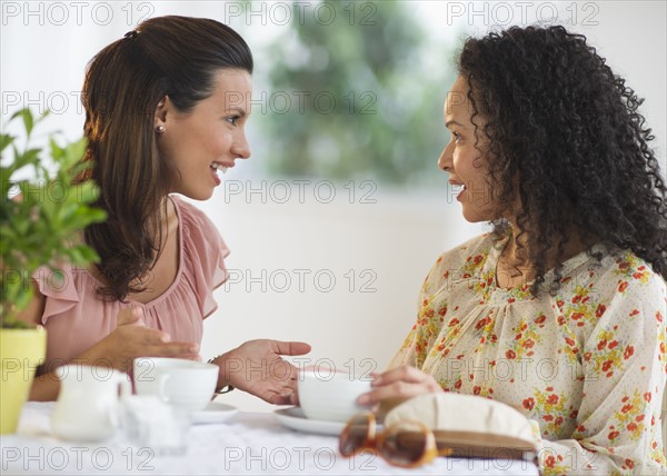 Two women chatting at cafe table.