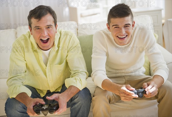 Father and son (16-17) playing video game.