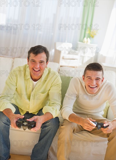 Father and son (16-17) playing video game.