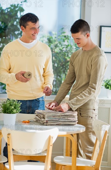 Father with teenage son (16-17) preparing paper for recycling.