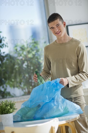 Teenager (16-17) recycling bottles.