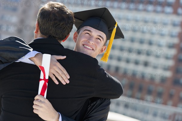 Father with teenage sun (16-17) at graduation ceremony.