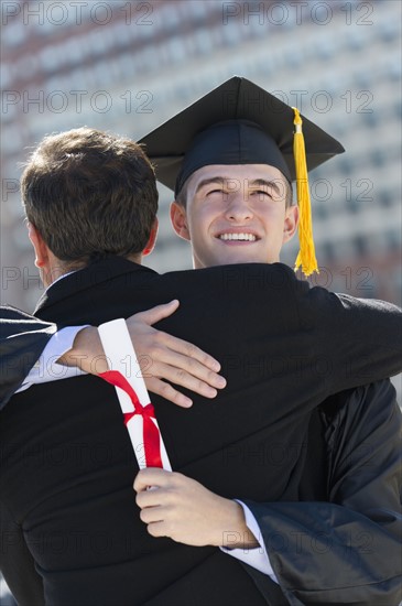 Father with teenage sun (16-17) at graduation ceremony.