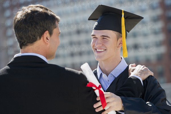 Father with teenage sun (16-17) at graduation ceremony.