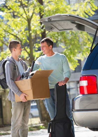 Father helping teenage son (16-17) packing to college.