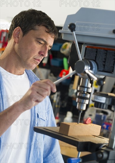 Mature man drilling in workshop.