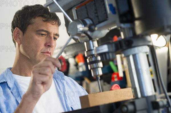 Mature man drilling in workshop.